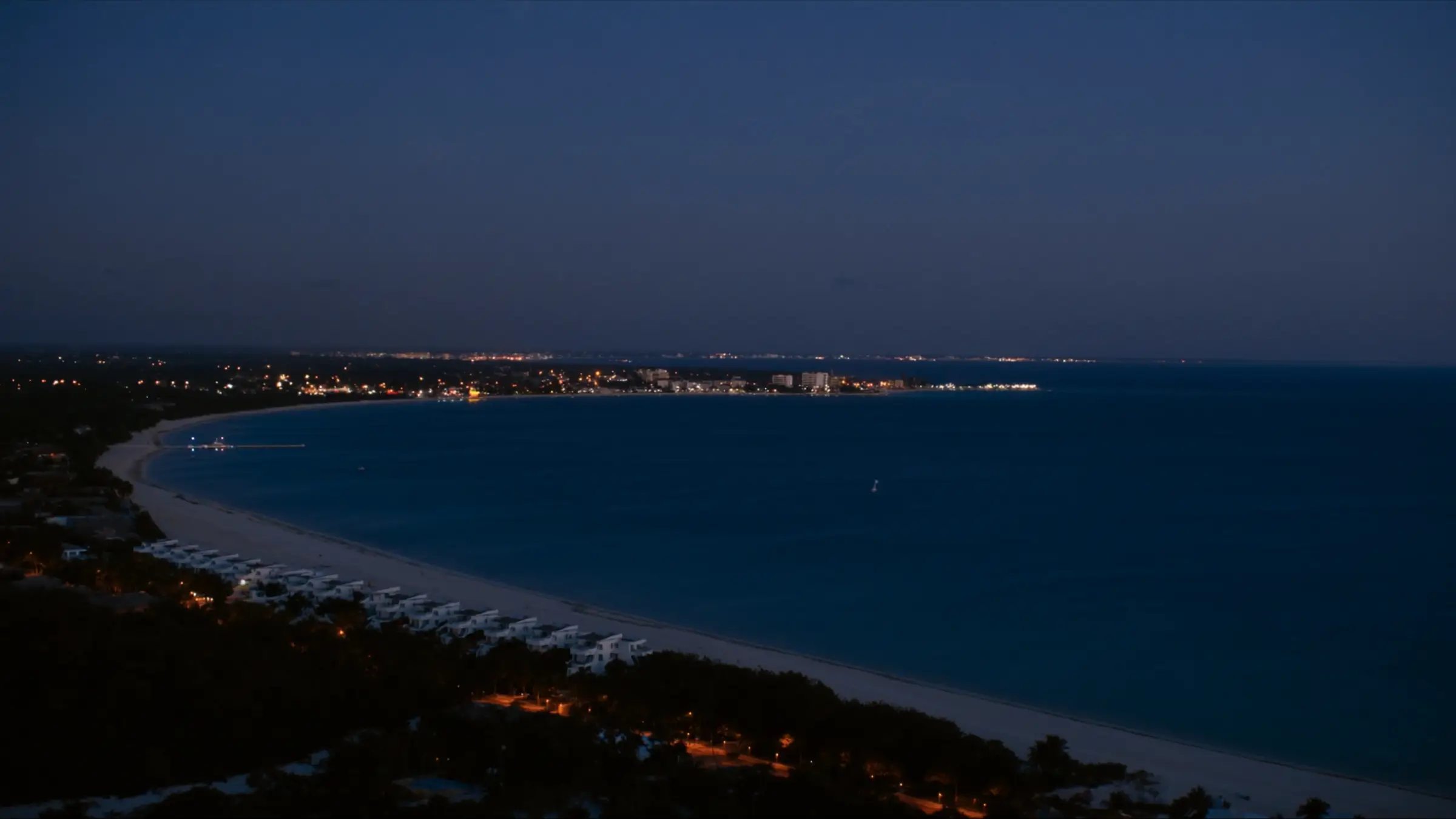 Bahía caribeña al anochecer, con las luces de la ciudad en el horizonte