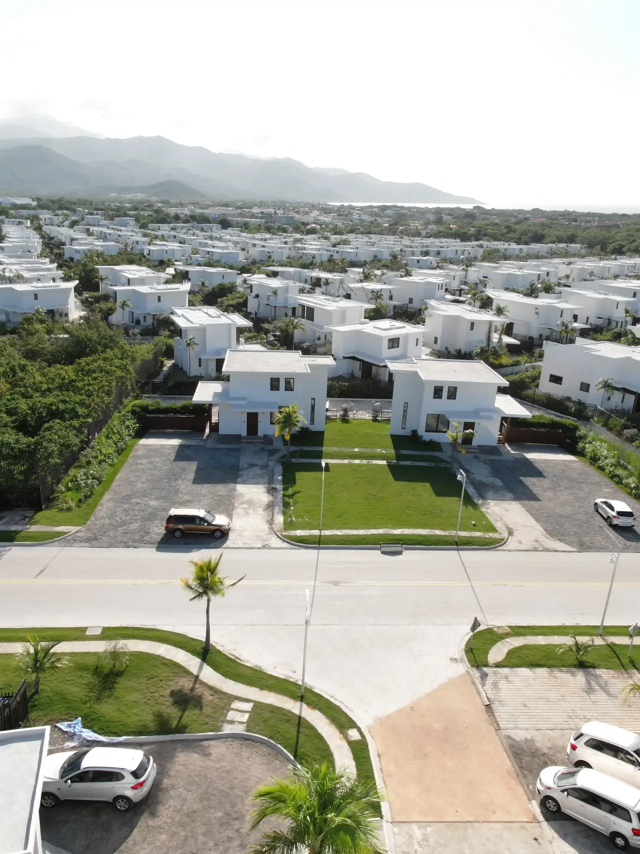 Vista aérea de una comunidad residencial con calles nuevas y montañas al fondo