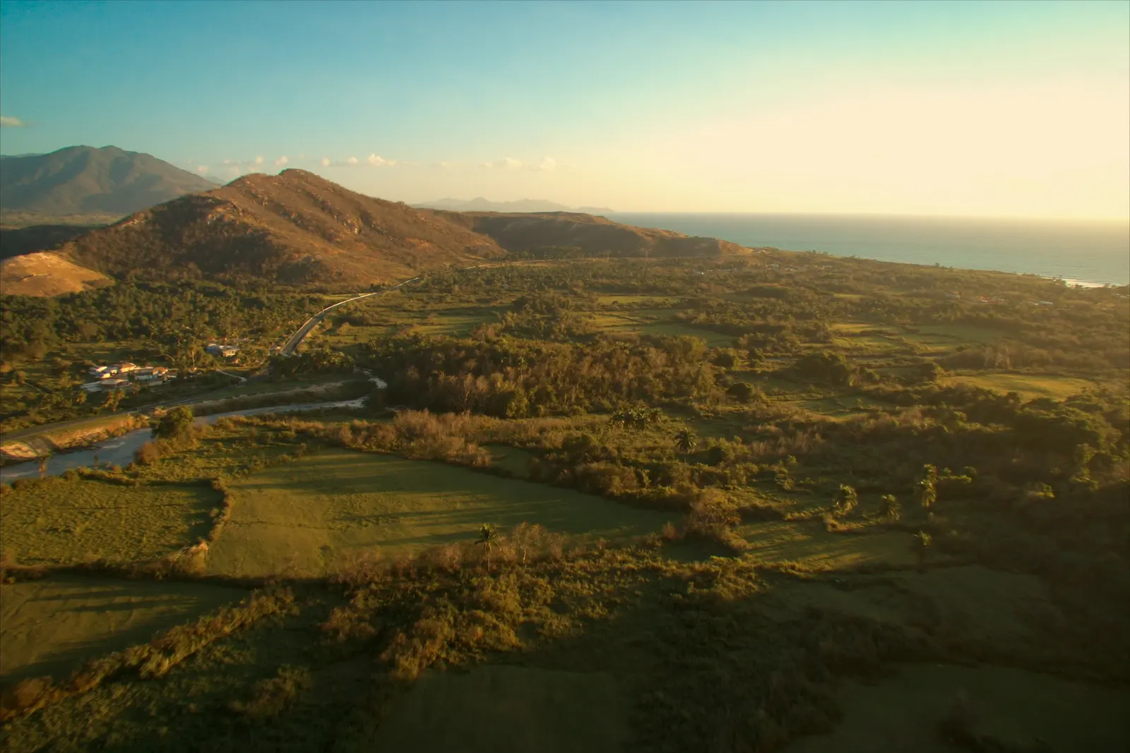 Vista aérea de la zona: montañas, valle cultivado, la carretera y el mar Caribe al fondo